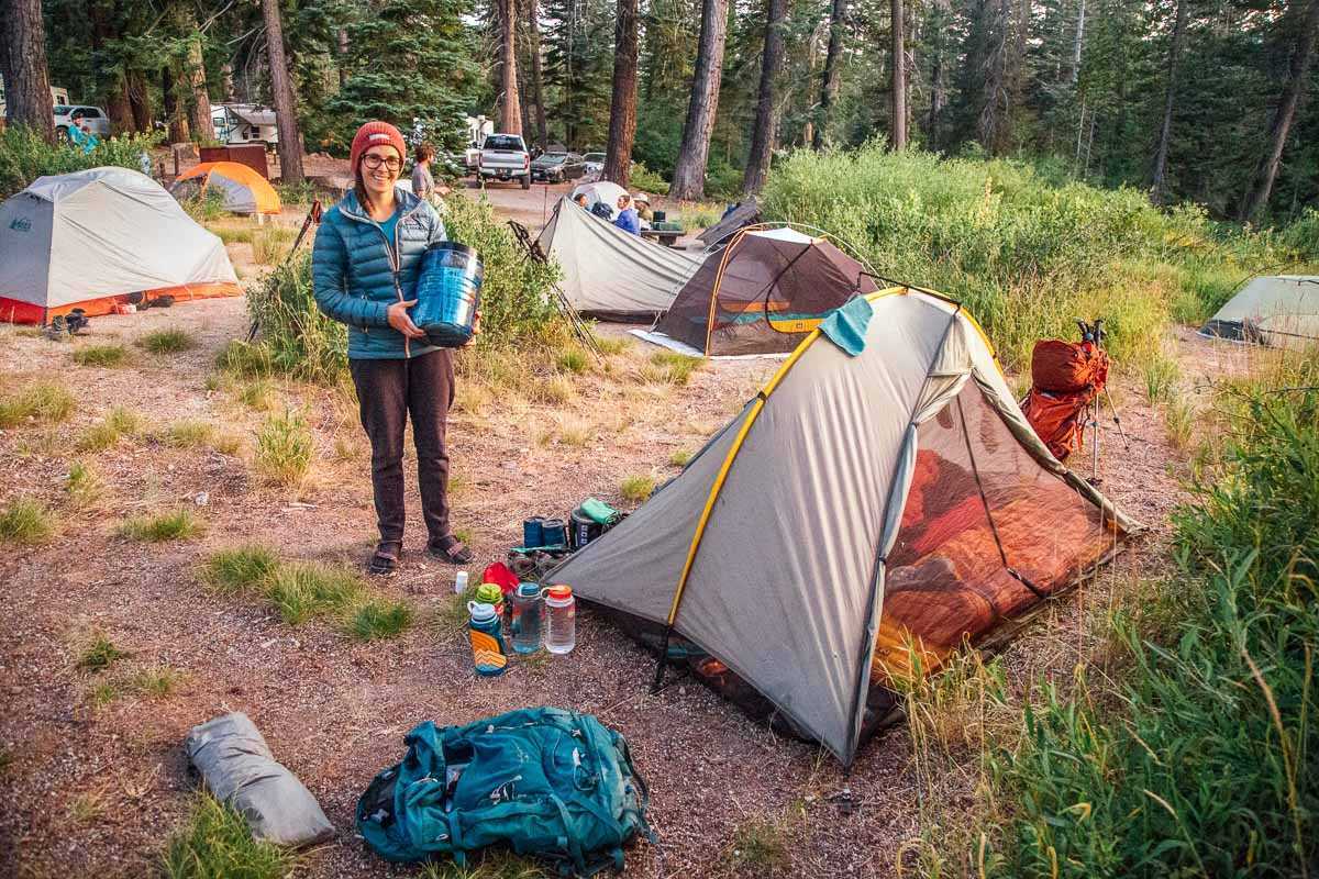 Меган держит медвежью бочку рядом с туристической палаткой