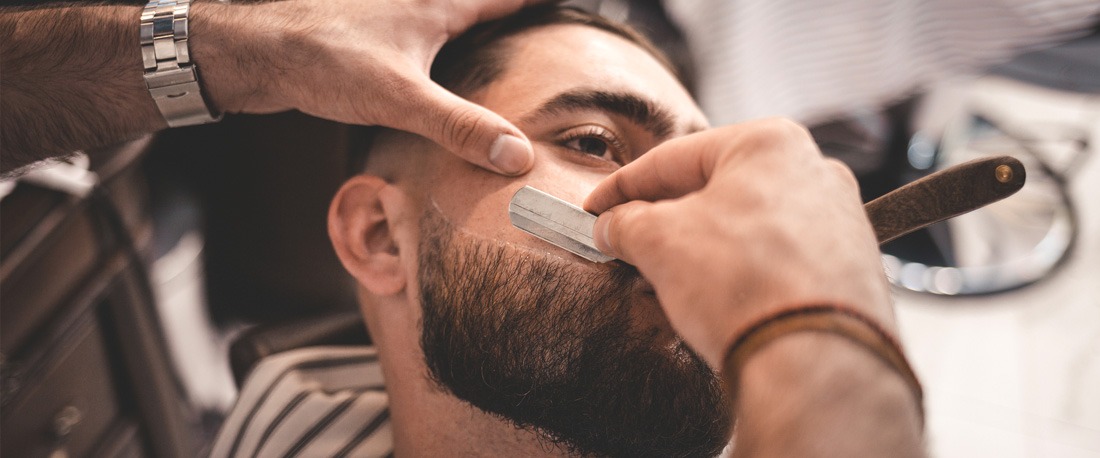 एक आदमी अपनी दाढ़ी एक सैलून में आकार लेता है