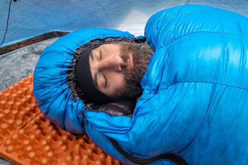   Bližnji posnetek kapuce Zpacks Mummy Bag, stisnjene okoli spečega moškega's face