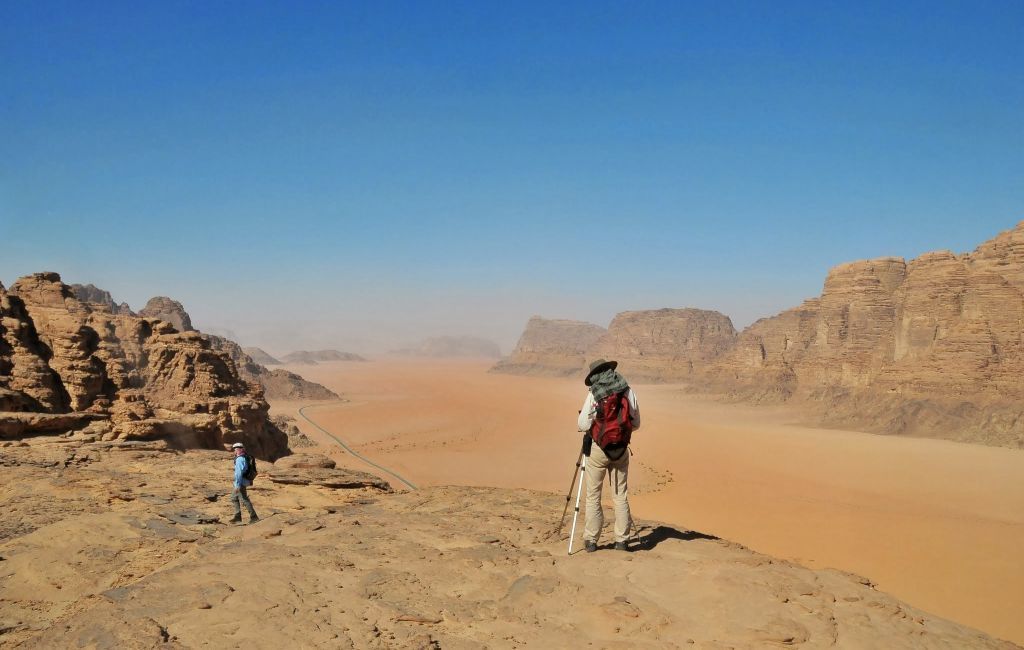 दो लोग लंबी पैदल यात्रा करते हुए रेगिस्तान के कपड़े पहनते हैं