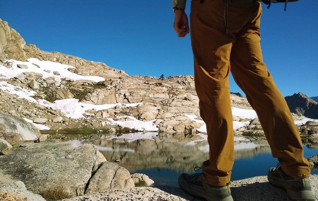 randonneur portant un pantalon de randonnée en face du lac