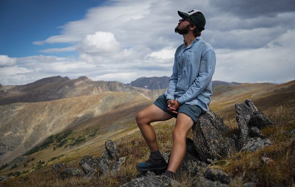 muški planinar odmarajući se na stijeni u planinarskoj majici s dugim rukavima od poliestera