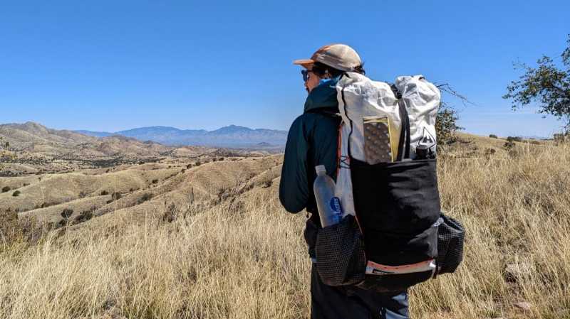   Ein Wanderer mit der Hyperlite Mountain Gear Unbound 40 blickt auf ferne Berge