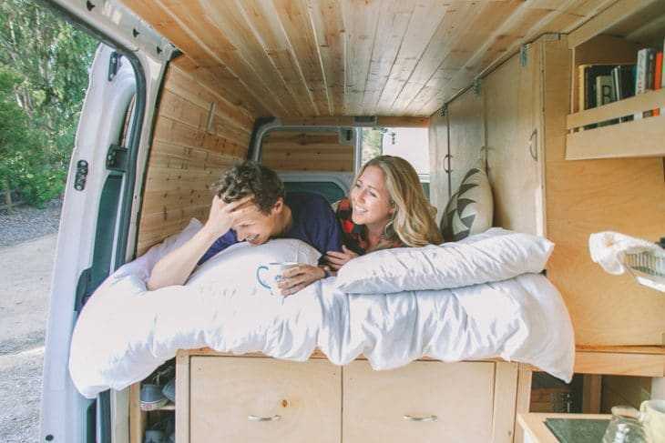 ชายและหญิงบนเตียงรถตู้ออกบ้านของพวกเขา