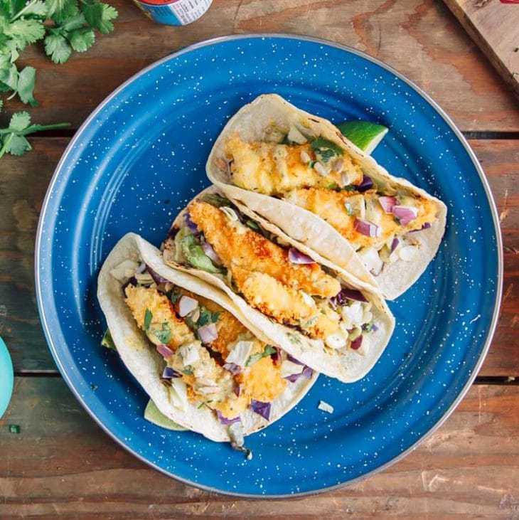 Trois tacos au poisson sur une assiette bleue