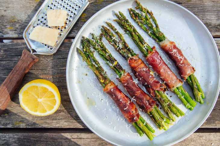 Binalot ng Prosciutto ang mga bundle ng asparagus sa isang plato