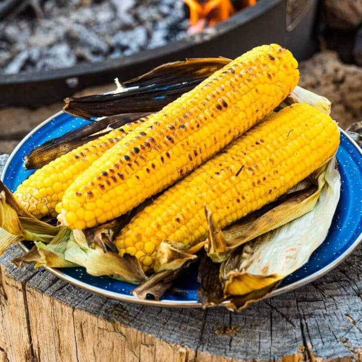 Mazorca de maíz asada apilada en un plato azul.