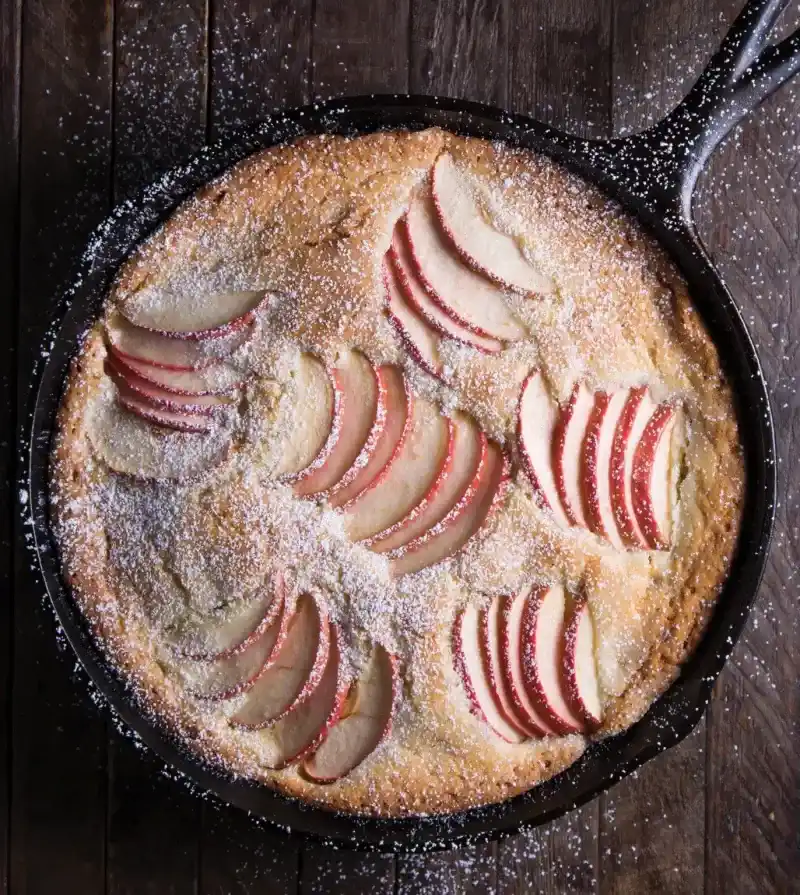   कच्चे लोहे की कड़ाही में सेब के स्लाइस के साथ केक।