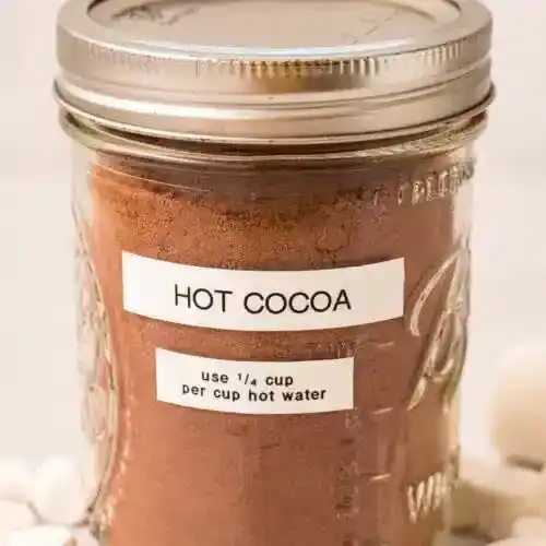   Egy befőttesüveg, benne forró kakaókeverékkel. A címkén ez áll: „forró kakaó, használjon ¼ csésze forró kakaót csésze forró vízhez”.
