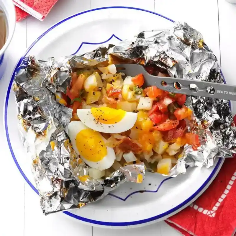   Un sachet en aluminium contenant des pommes de terre, des œufs et des tomates.