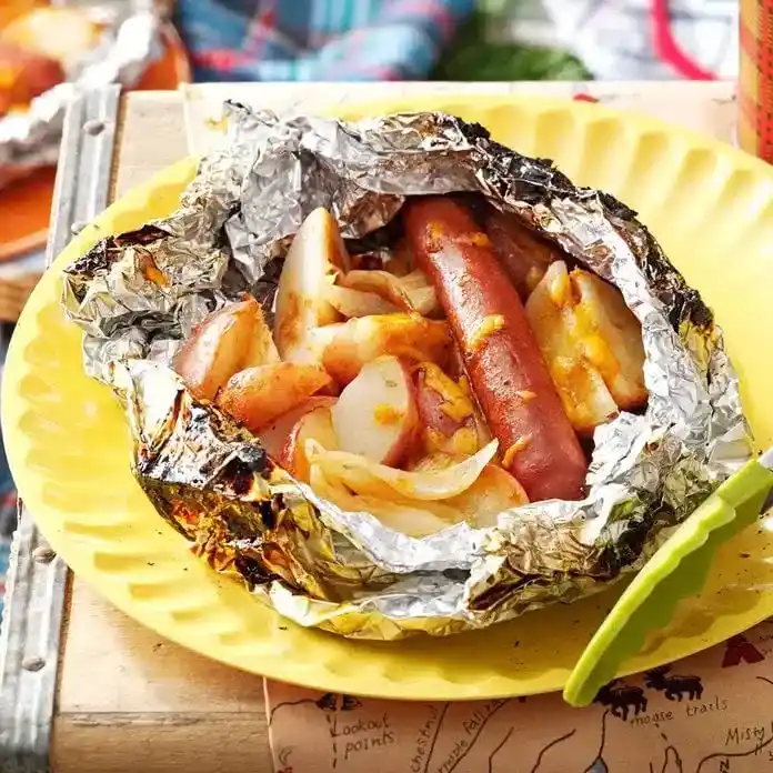   Patatas y un hot dog en papel de aluminio servido en un plato amarillo.