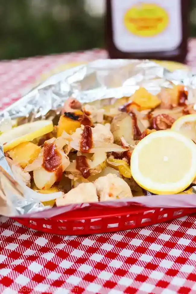   Kırmızı beyaz kareli masa örtüsünün üzerinde folyoya sarılı tavuk ve ananas parçaları.