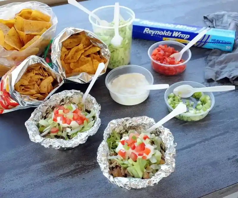   Foliepakketten met taco-ingrediënten op een houten tafel.
