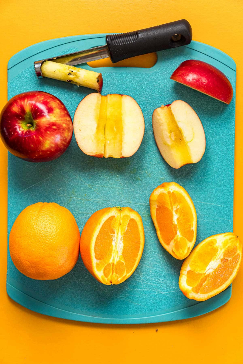   Pommes et oranges en quartiers sur une planche à découper.