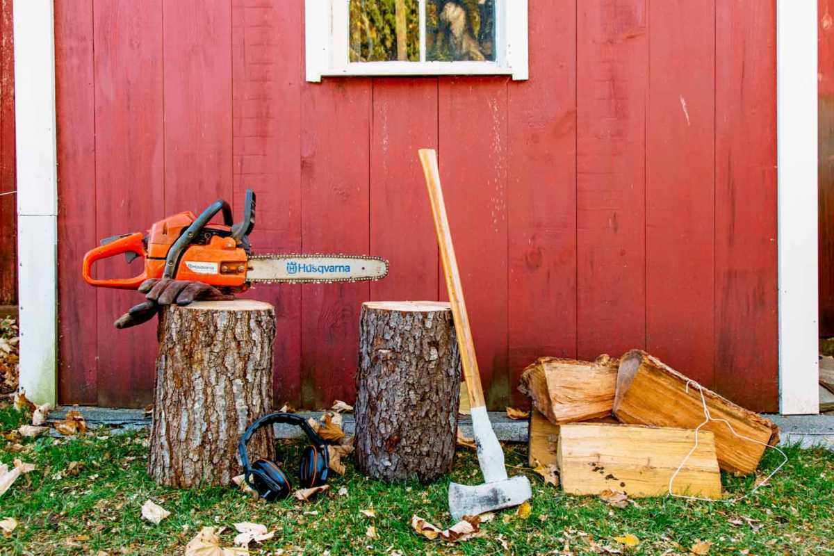 赤い小屋の前にある薪と木の切削工具
