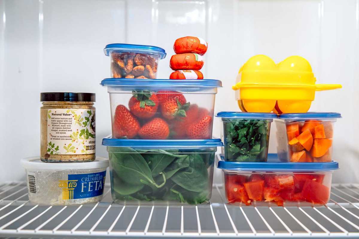 Contenitori ermetici di alimenti impilati su un ripiano del frigorifero.