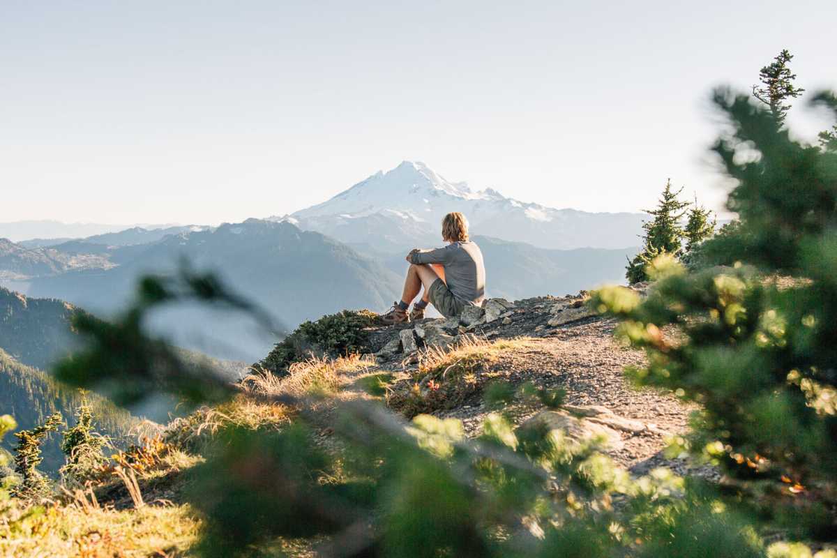 Michele seduto su uno sperone roccioso con una montagna in lontananza