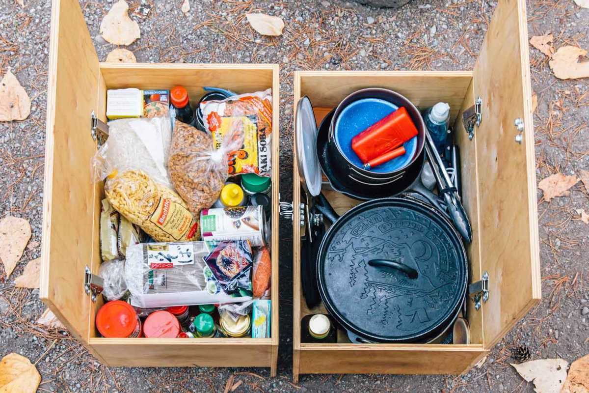 Dos cajas de madera llenas de ingredientes de despensa y equipo de cocina para acampar