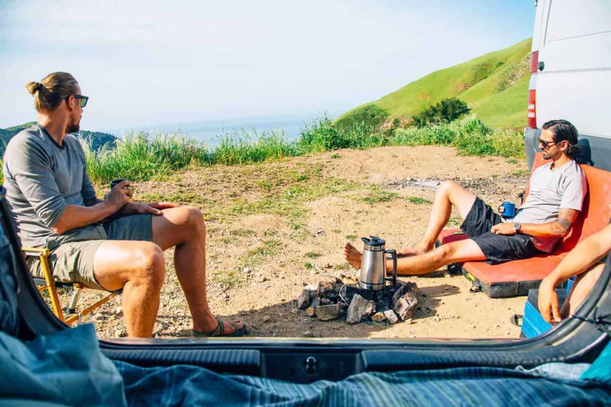 Divi vīrieši sēž ap ugunskuru Big Sur