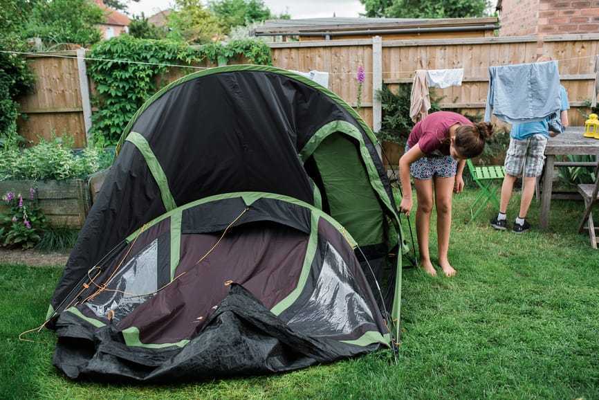 En pige, der slår et telt op i baghaven