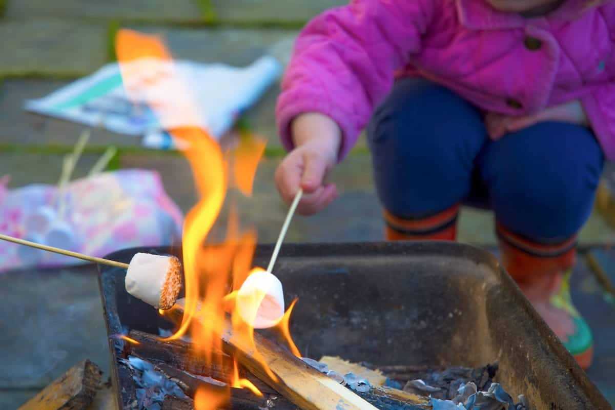 Dieťa pečie marshmallow nad ohniskom.