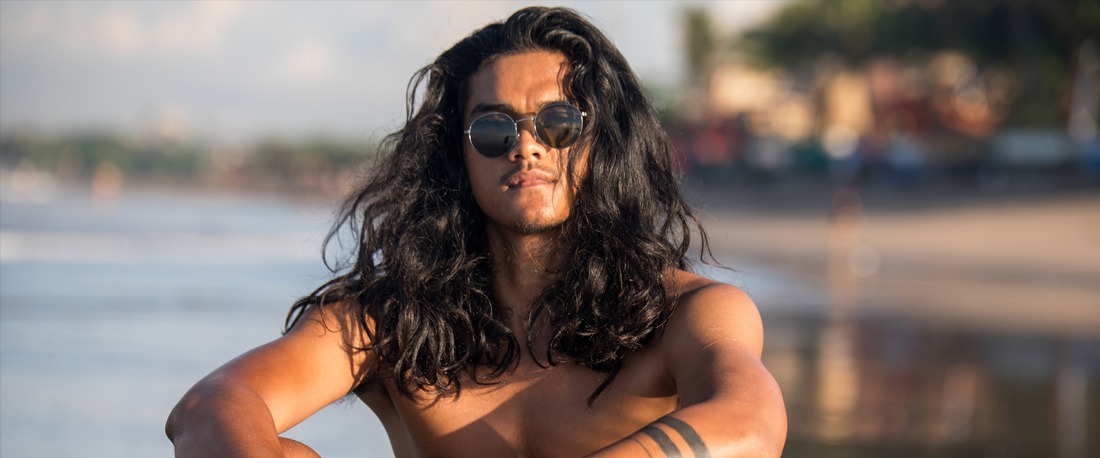 Seorang lelaki dengan gaya rambut kerinting panjang di pantai