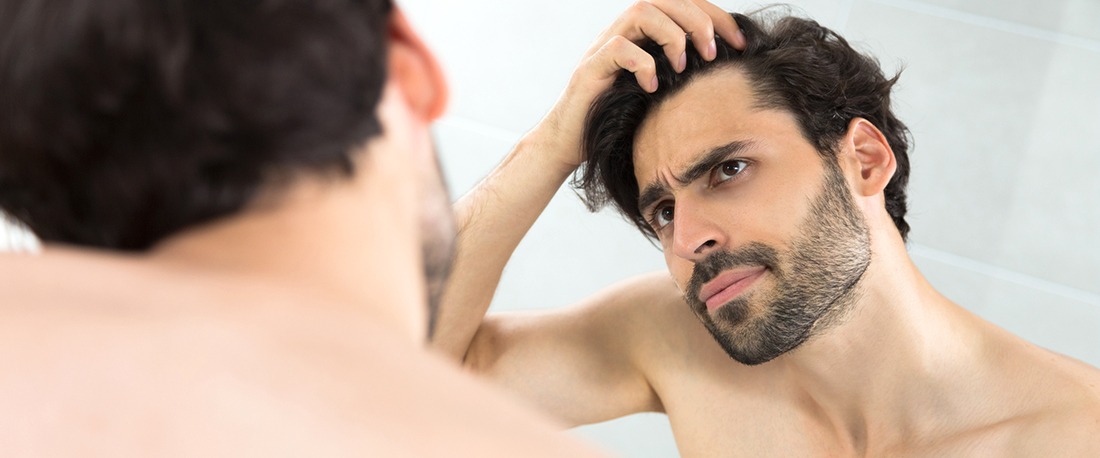 En ung mann som prøver å tilføre volum i håret