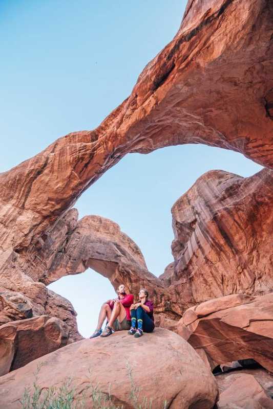 Megan e Michael seduti su una roccia osservano il doppio arco nel Parco nazionale degli Arches