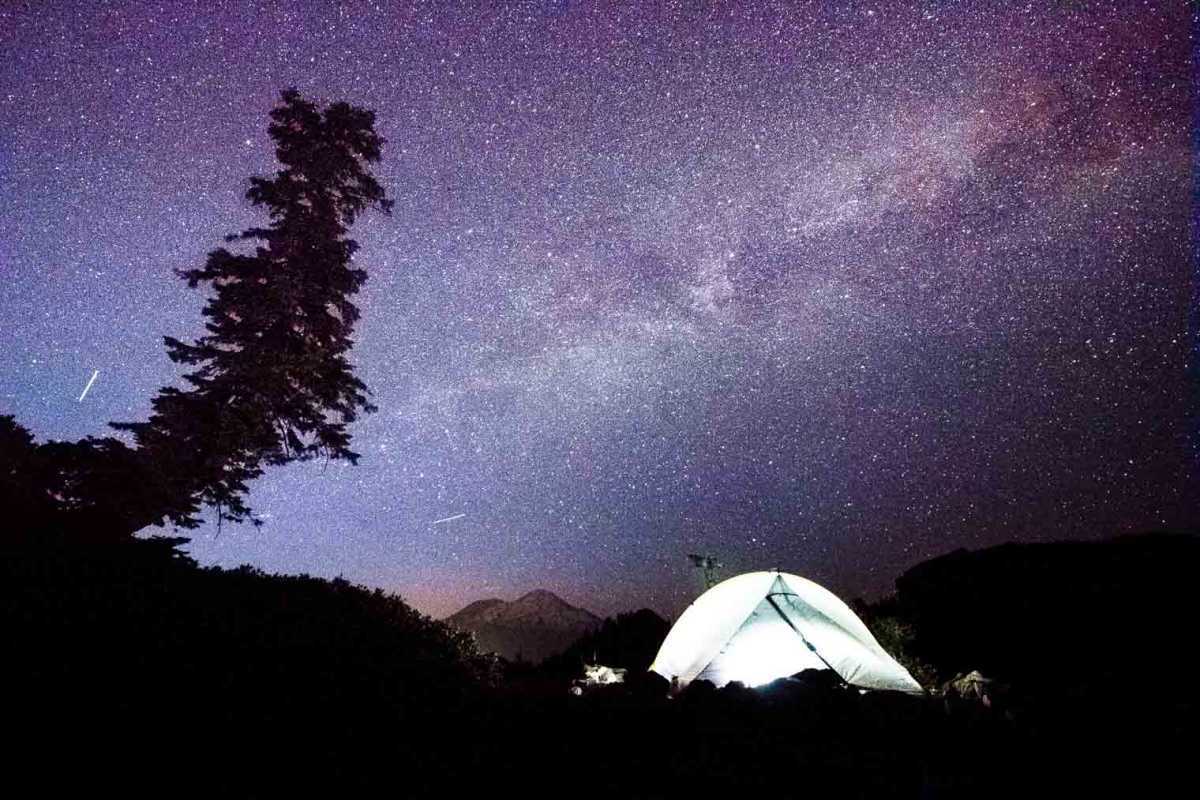 La silhouette di una tenda contro un cielo stellato