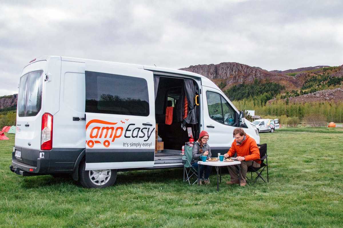 Bir karavan minibüsünün önünde yemek yiyen bir çift