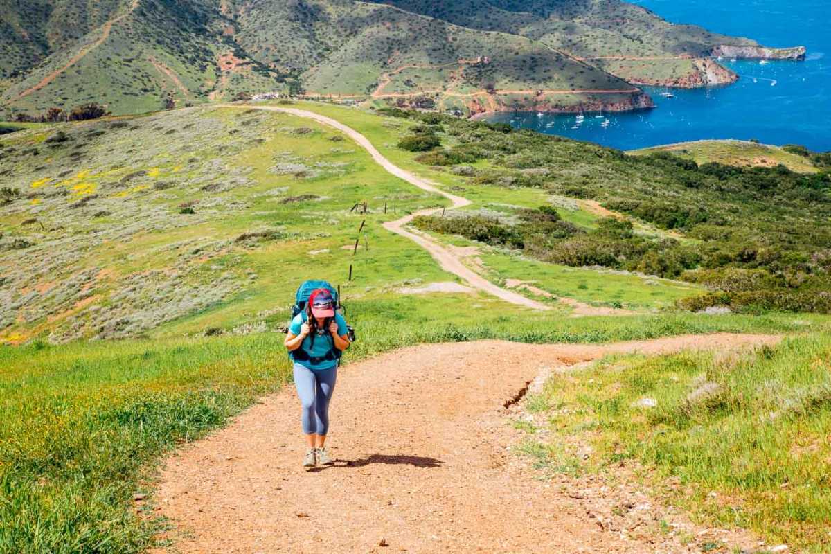Một người phụ nữ đi bộ lên ngọn đồi dốc quanh co trên Đường mòn Trans Catalina