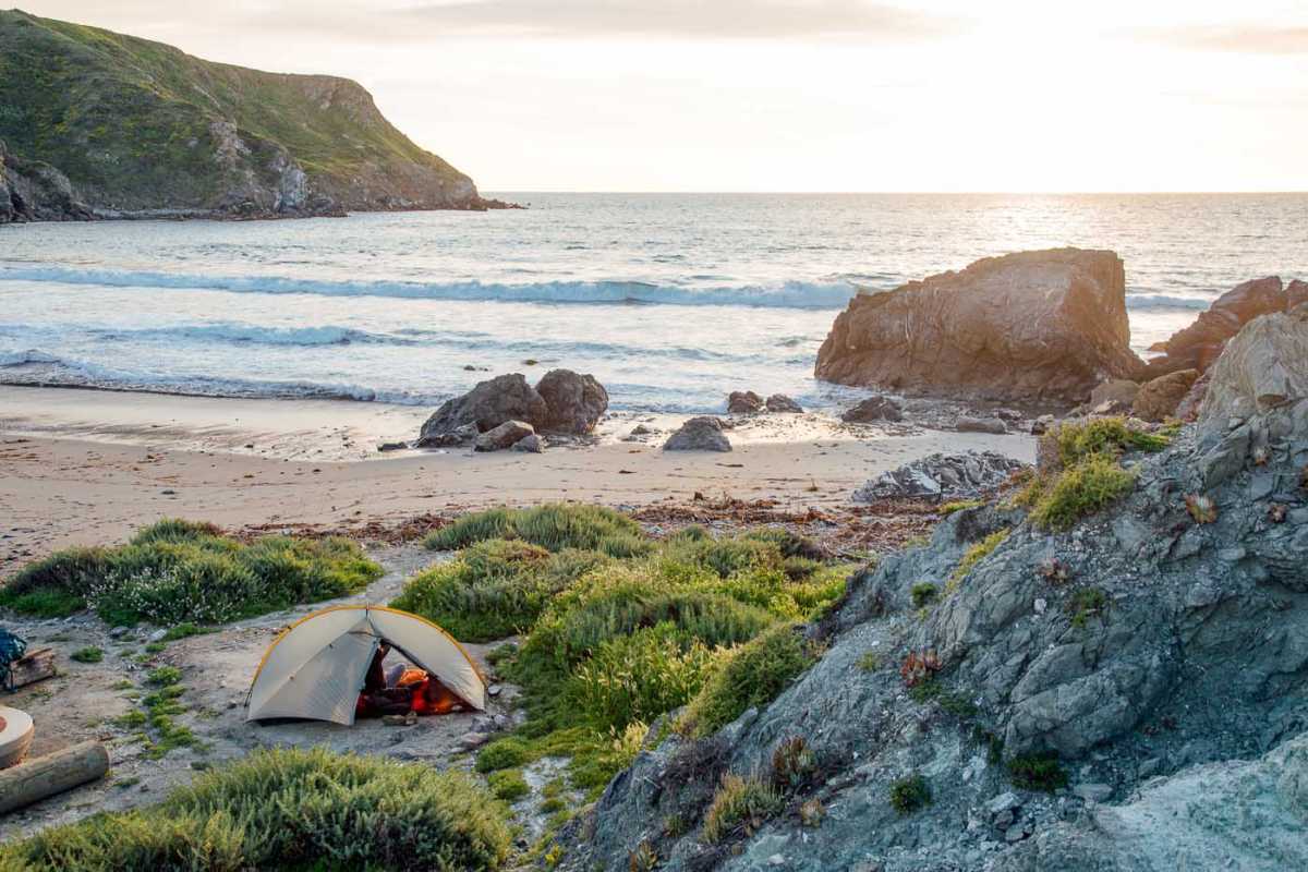 A tengerparton felállított sátor, kilátással az óceánra naplementekor.