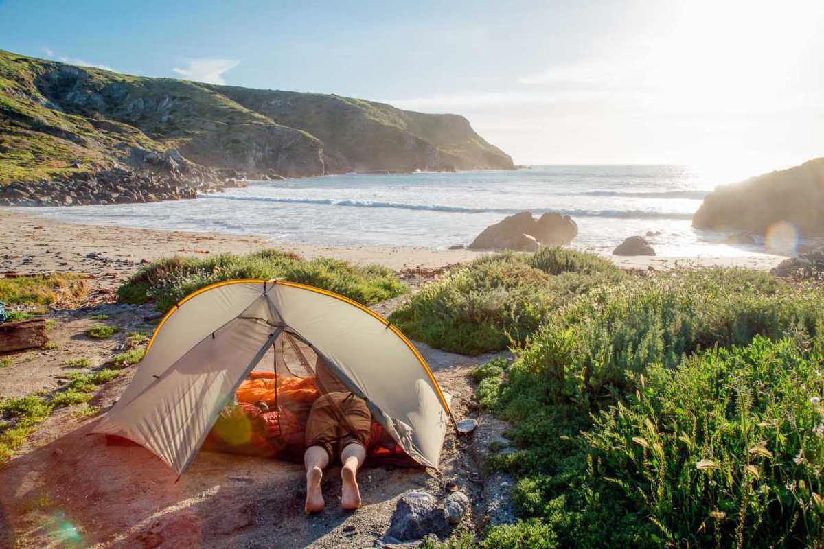Човек у шатору на плажи у луци Шарк, острво Каталина