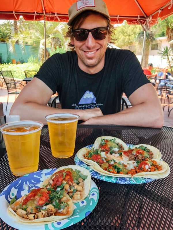 Hymyilevä mies istuu taco-lautasen edessä