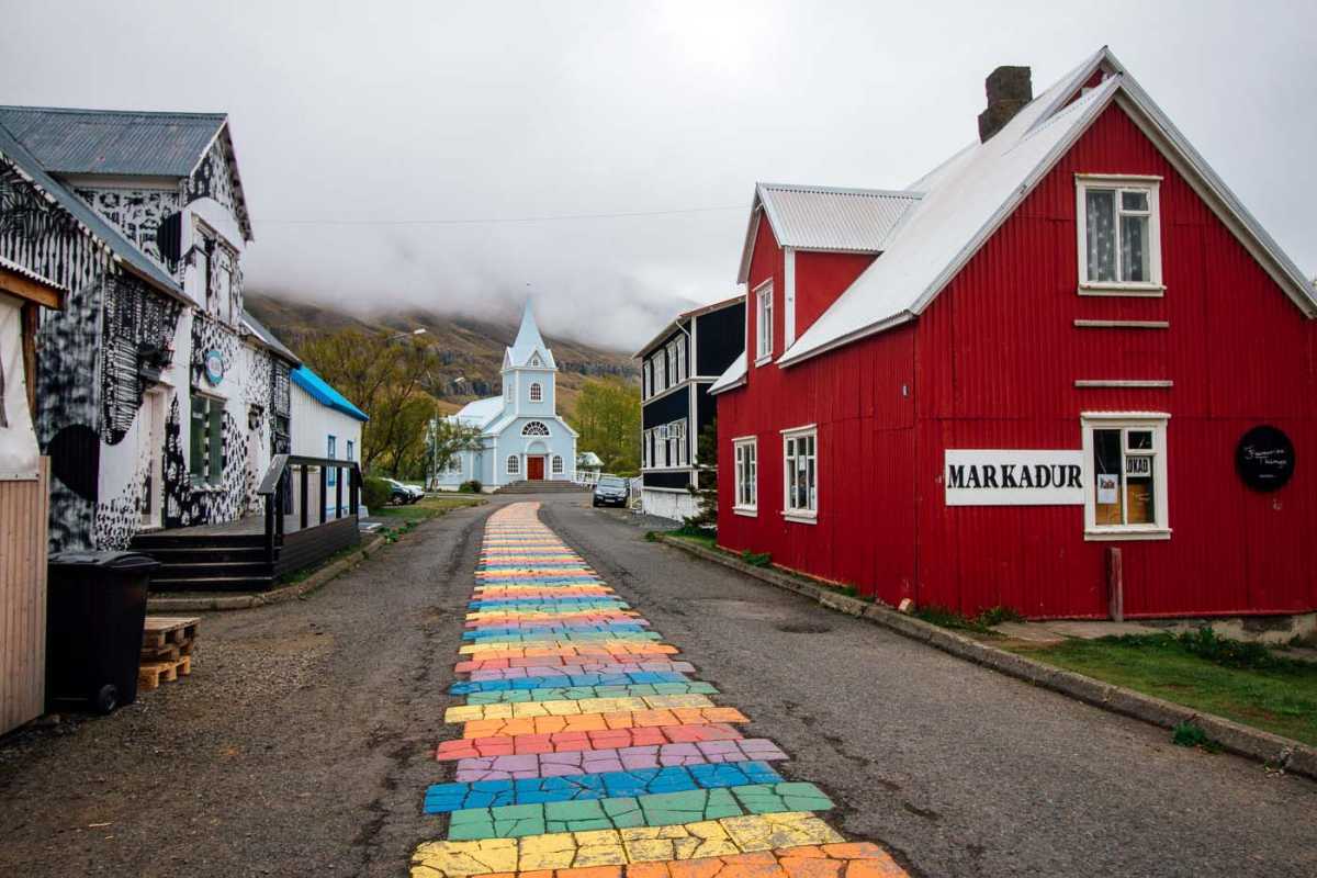 Camino pintado del arco iris que conduce a una iglesia azul