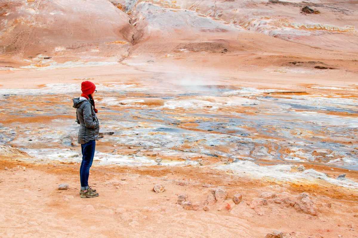 Женщина стоит перед геотермальным полем Хверир