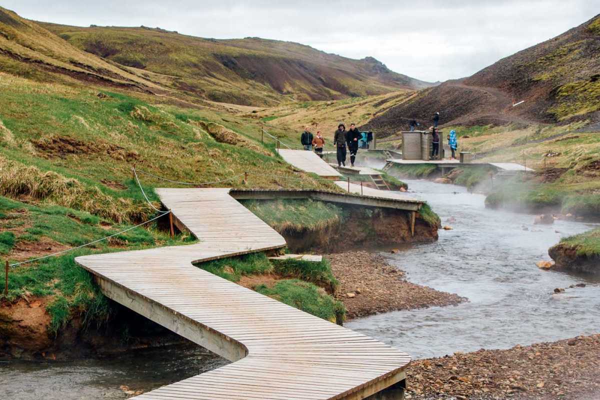 En strandpromenade i tre som slynger seg rundt Reykjadalur Hot Spring Thermal River