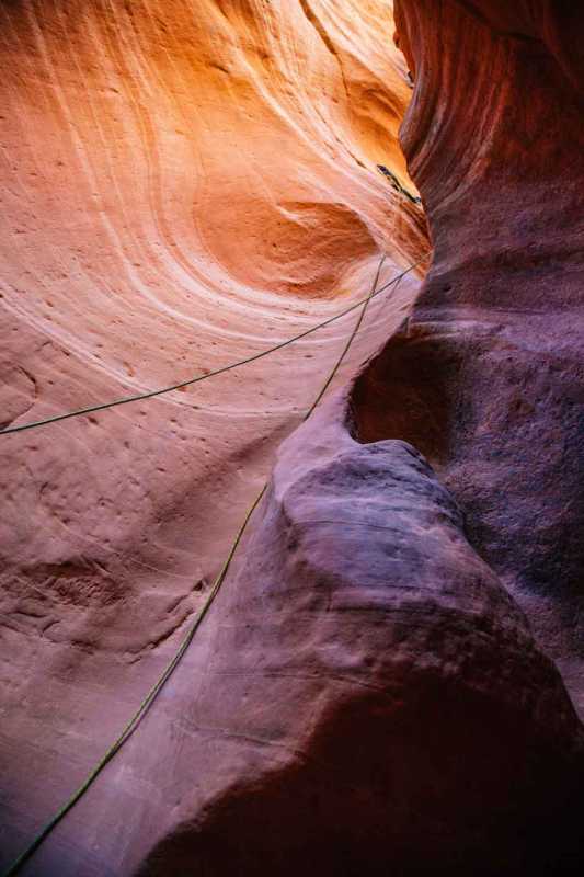 Uno slot canyon rosa e arancione con corde da arrampicata appese alle pareti