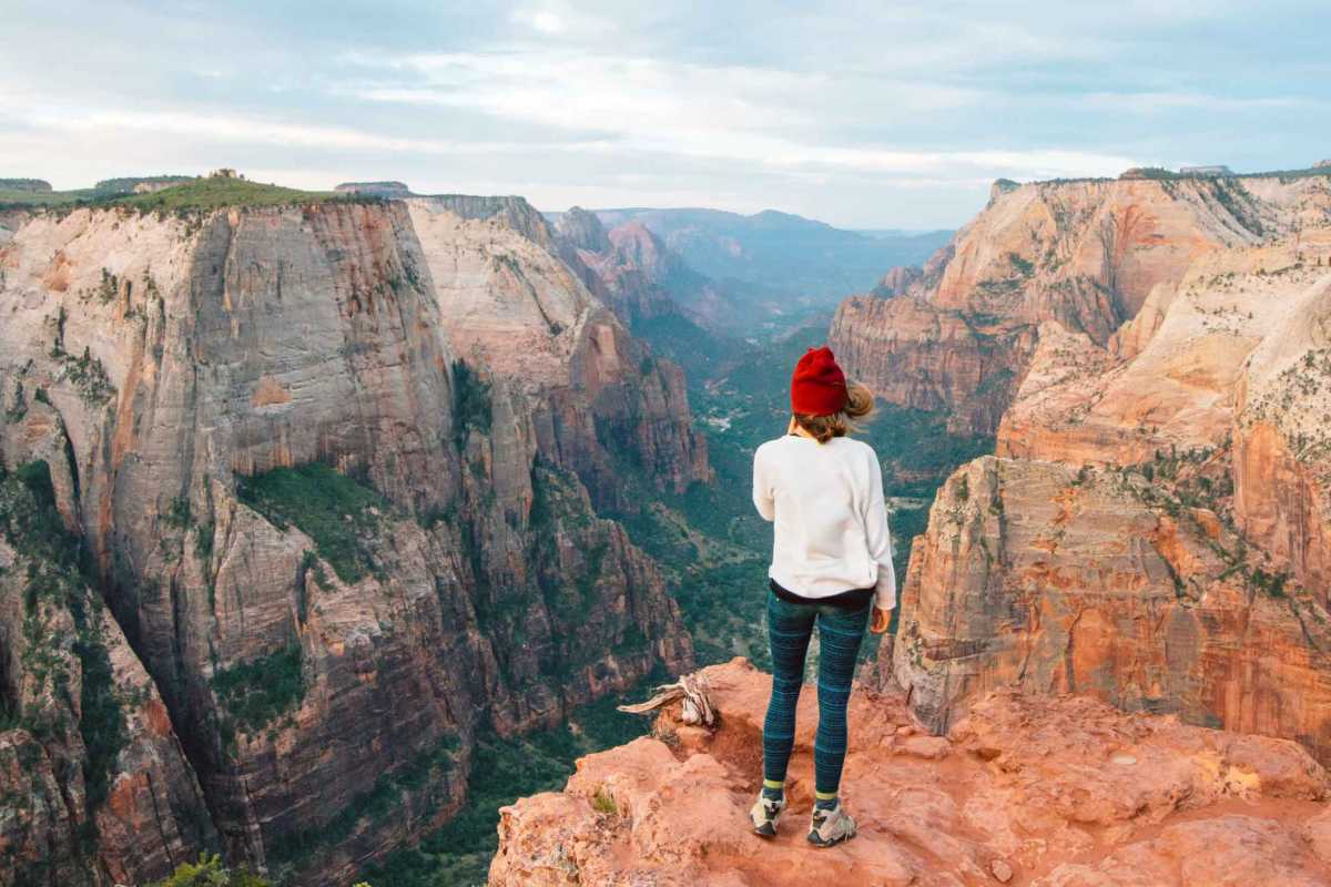 Megan staat op een rots bij een observatiepunt en kijkt neer in de Zion Canyon