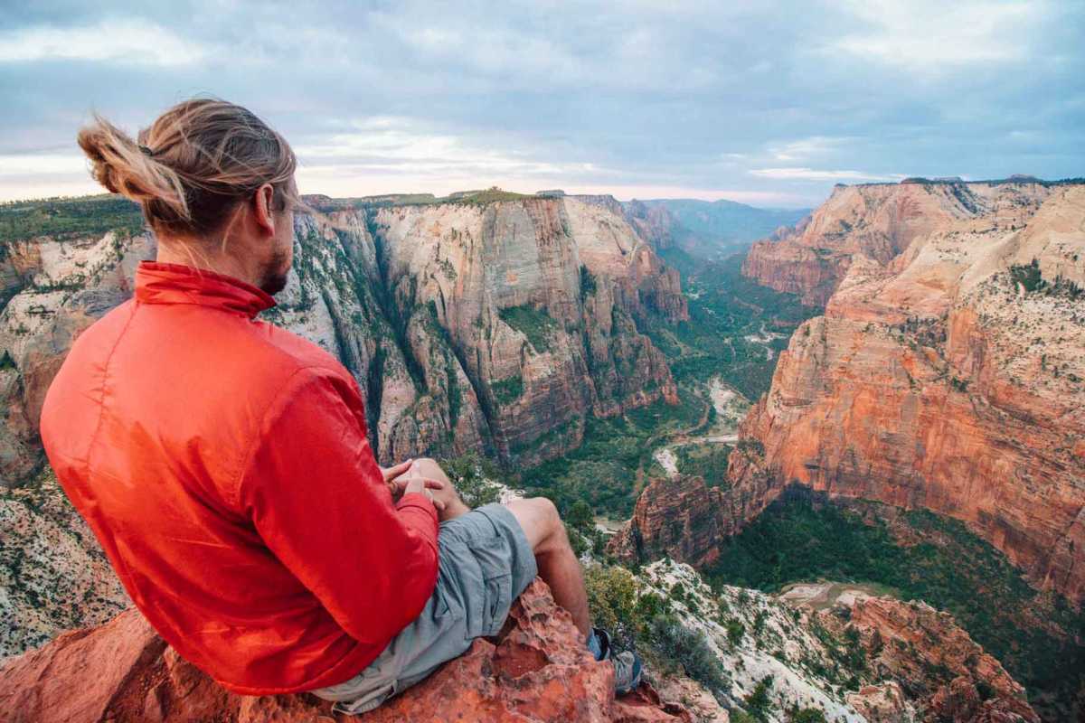 Michael sentado en una roca en el punto de observación mirando hacia Zion Canyon