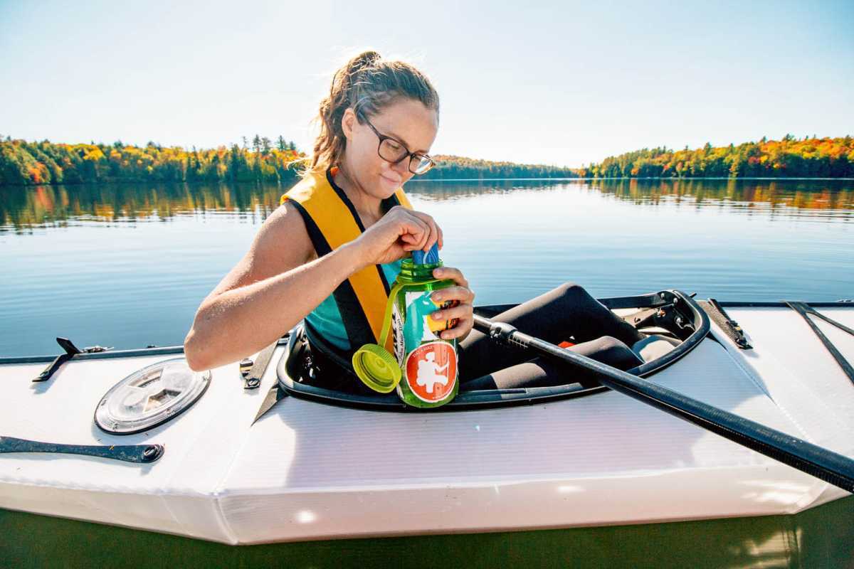 Megan est assise dans un kayak et utilise un steripen dans une bouteille d