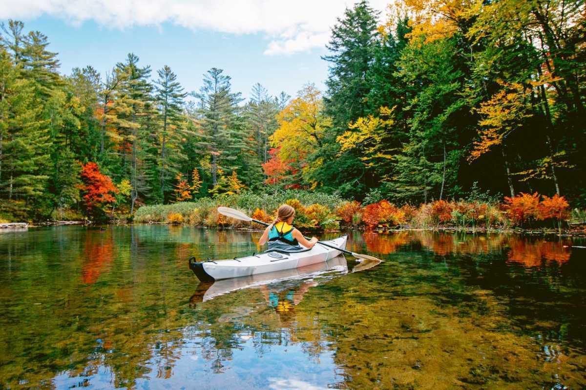 Megan en kayak con follaje de otoño alrededor