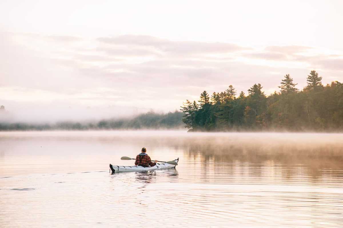 Michael navega en kayak por la mañana en aguas tranquilas y brumosas.