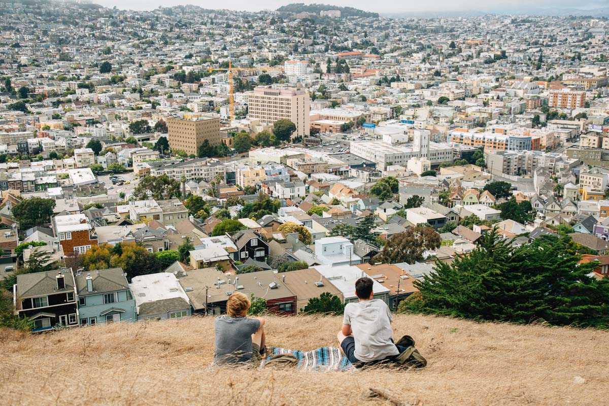 Майкъл и негов приятел седят на хълма Бернал с изглед към град Сан Франциско