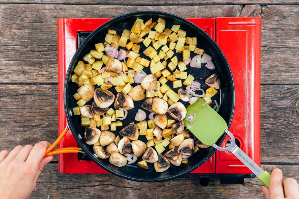 Kepkite kubeliais supjaustytas bulves, ketvirčiais supjaustytus grybus ir askaloninius česnakus didelėje keptuvėje tofu plakiniui