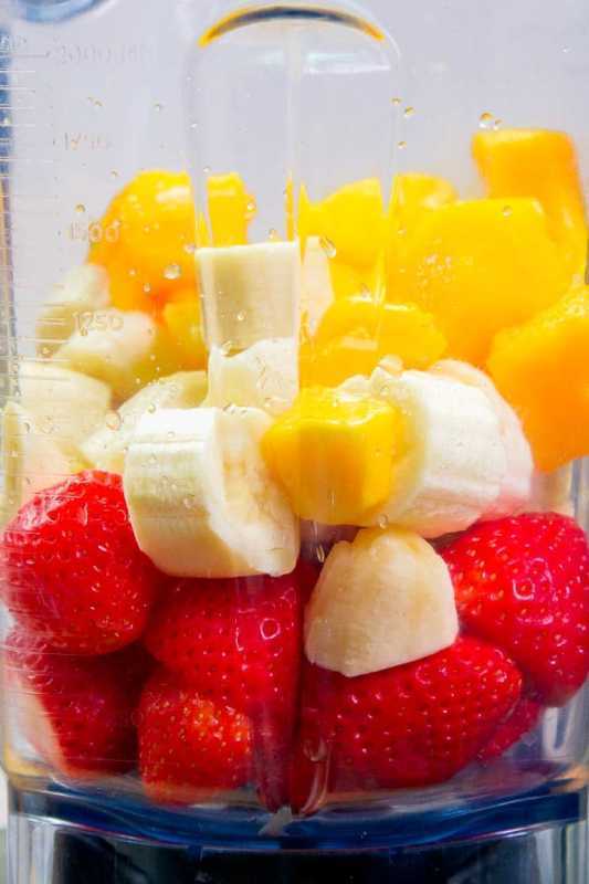 Coupez les fraises, les mangues et les bananes dans un mixeur.