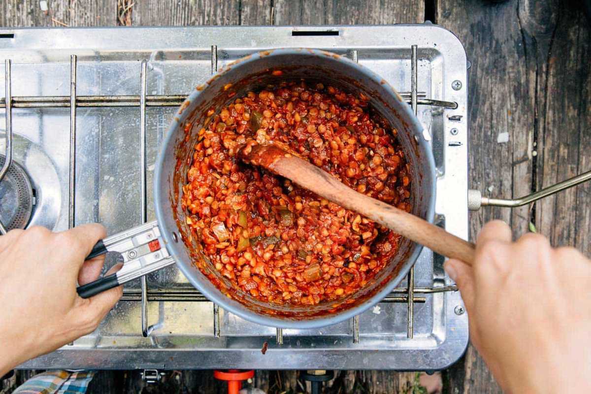 キャンプ用ストーブの上の鍋で調理する赤レンズ豆のスルージョーズ