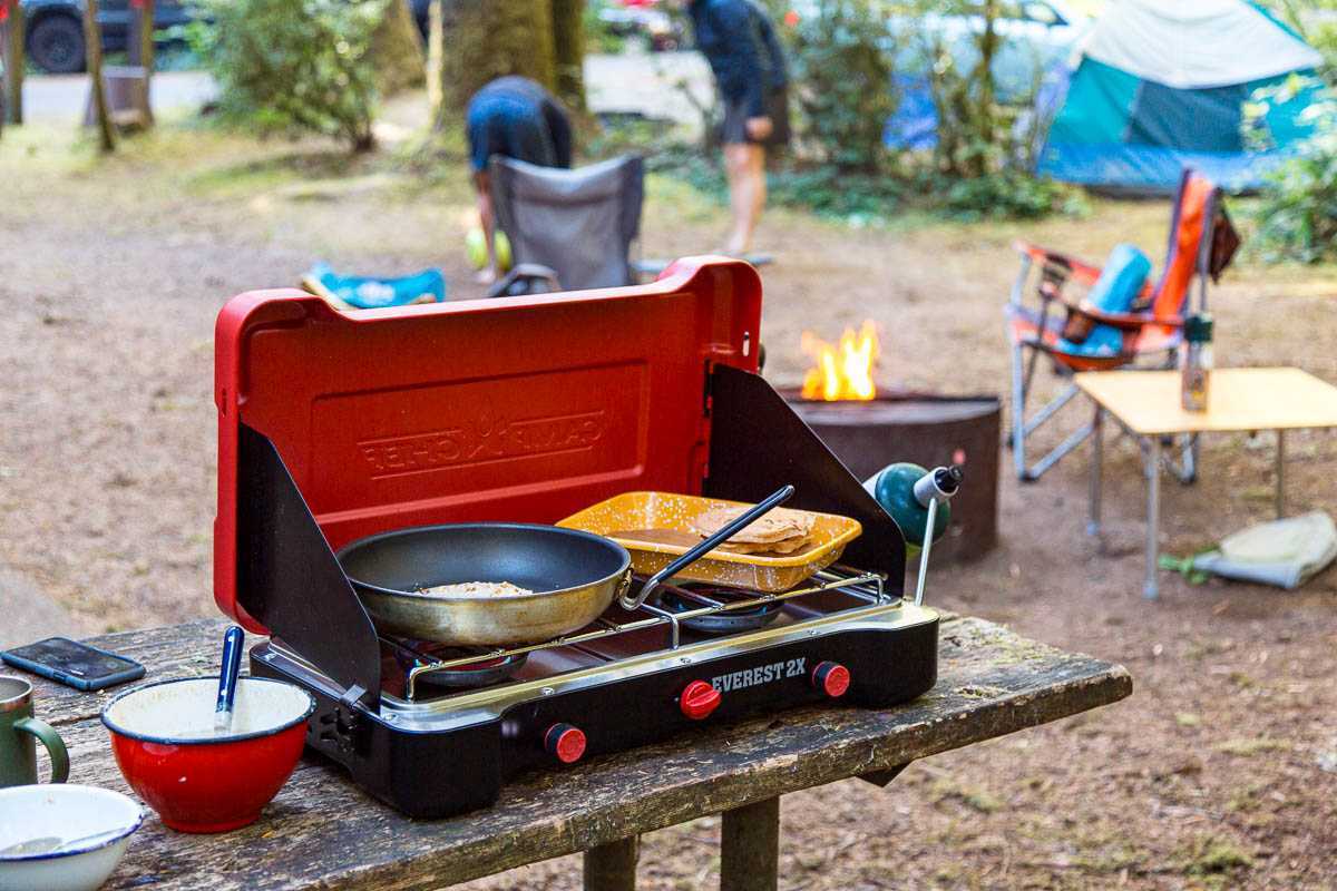Kawali sa isang camp stove na may background sa camping scene.