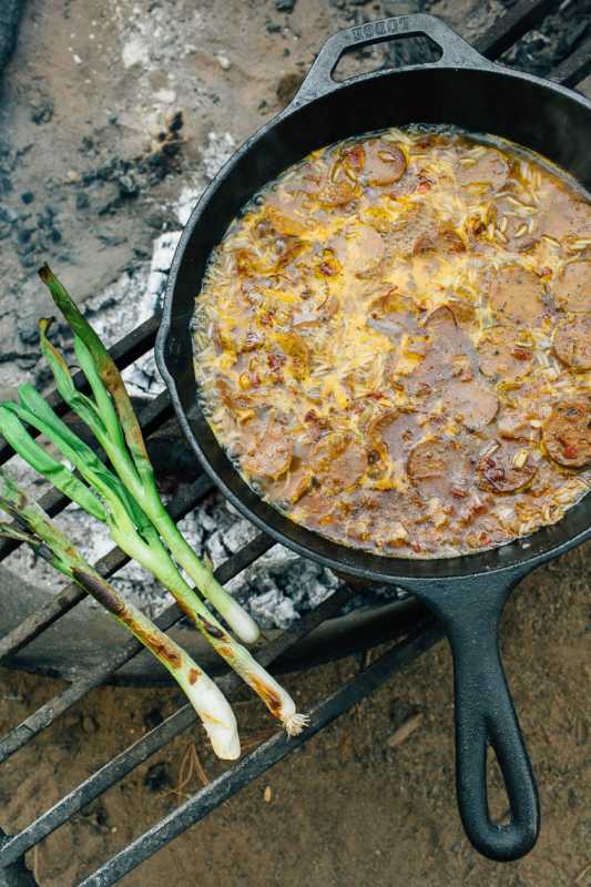 Kamp ateşinde dökme demir tavada pişirilen paella