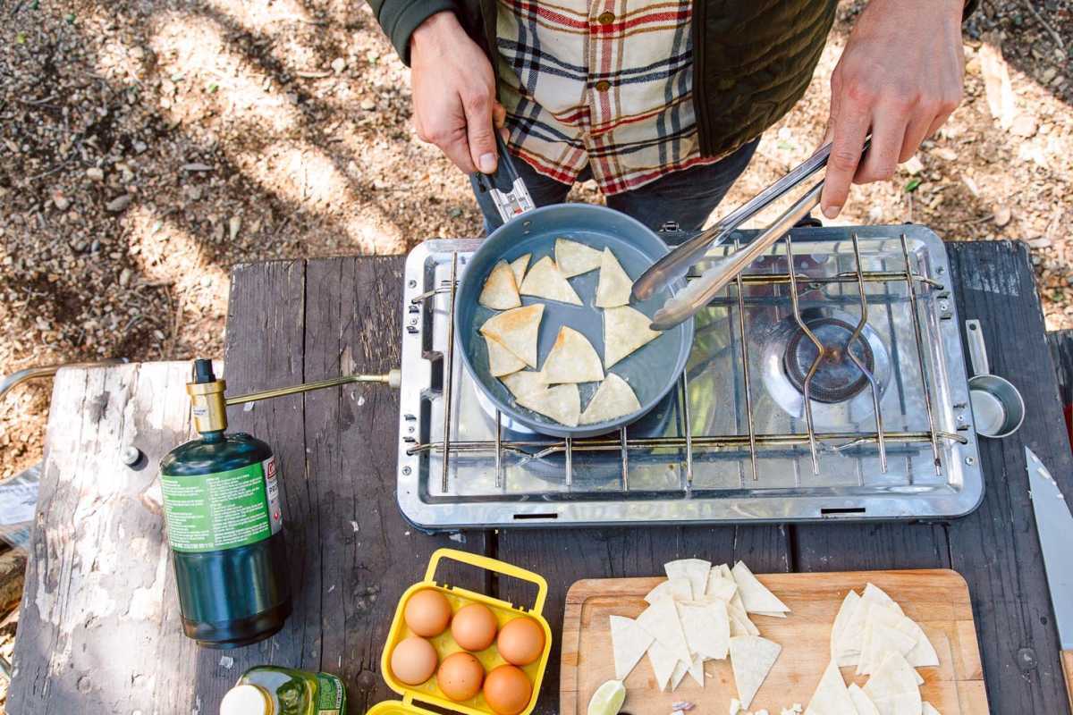 Chilaquiles é uma ideia fácil para o café da manhã de acampamento - tortilhas crocantes cozidas em molho de tomate picante e cobertas com ovos. Leva menos de 30 minutos para fazer e
